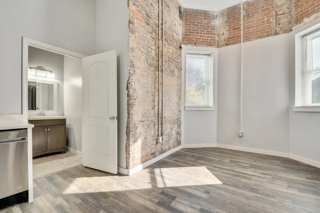 interior wall with exposed brick and view of bathroom