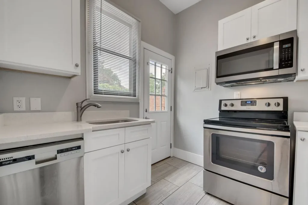 interior kitchen with stainless microwave, stove, and dishwasher, sink and exterior door in photo